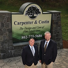 Carpenter and Costin owners stand next to their business sign