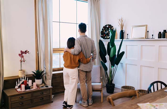 Couple Looking out a Window at Home