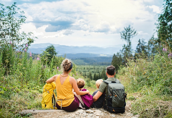 A family of four sits to rest and enjoy the view after hiking up a mountain