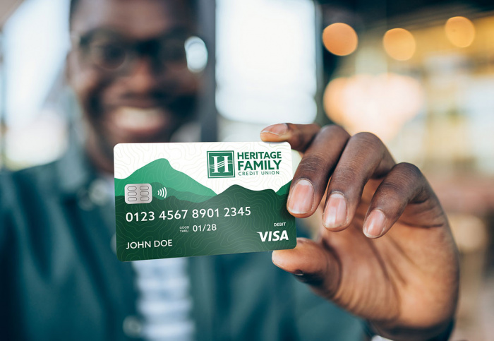 Man holding up HFCU debit card