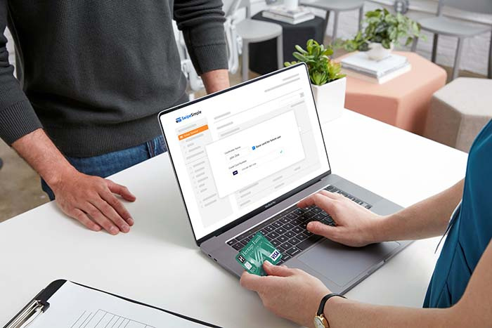 Image of a person using a laptop to process a credit card payment
